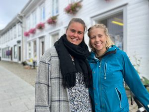 Bilde av Marit og Lina som står sammen og smiler i gågata i Tvedestrand.