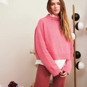 En kvinne er ikledd Wendy Sweater strikket i Bubblegum pink farge