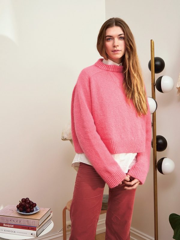 En kvinne er ikledd Wendy Sweater strikket i Bubblegum pink farge